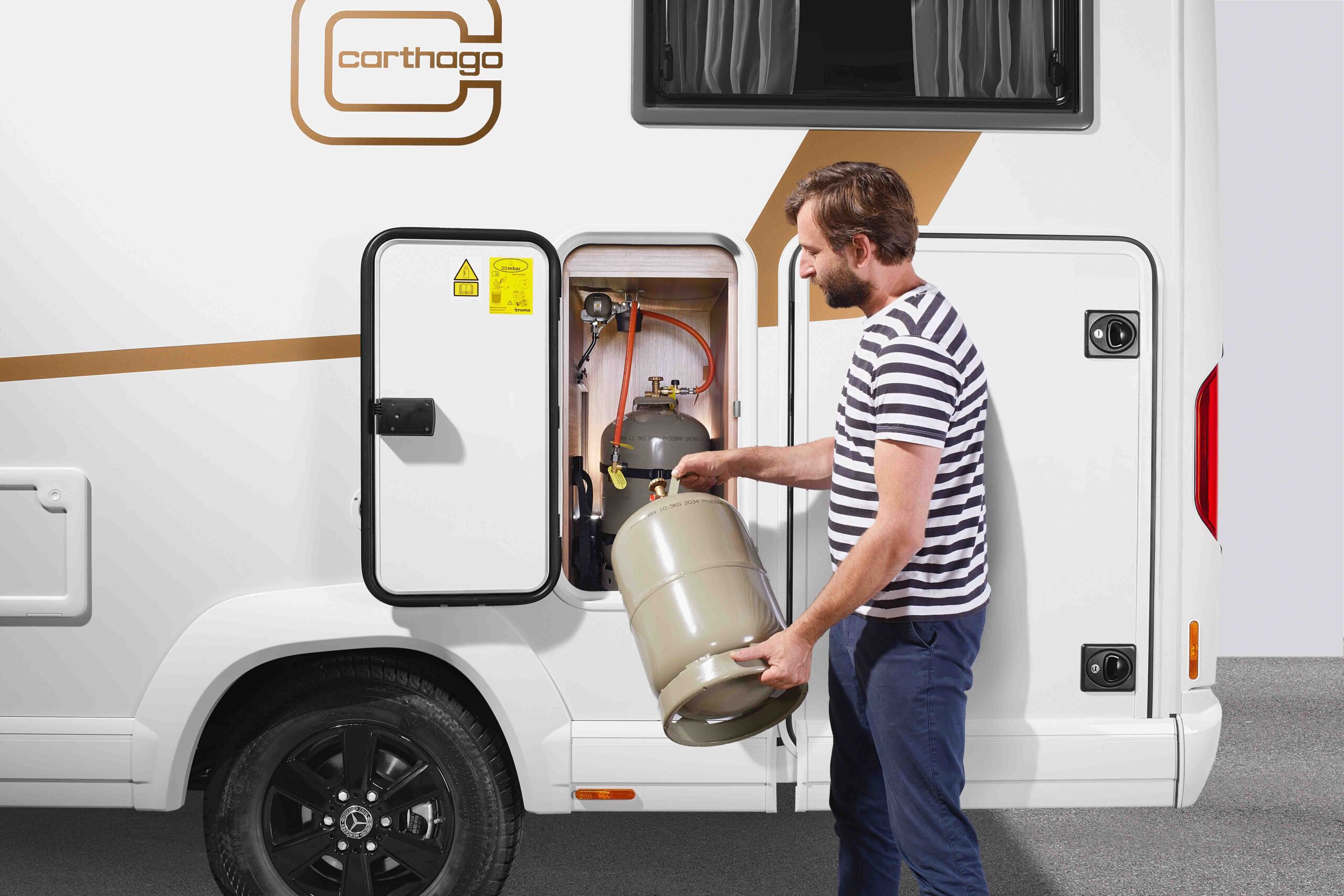 Mann entnimmt eine Gasflasche aus dem Gasflaschenkasten eines Carthago c2-tourer