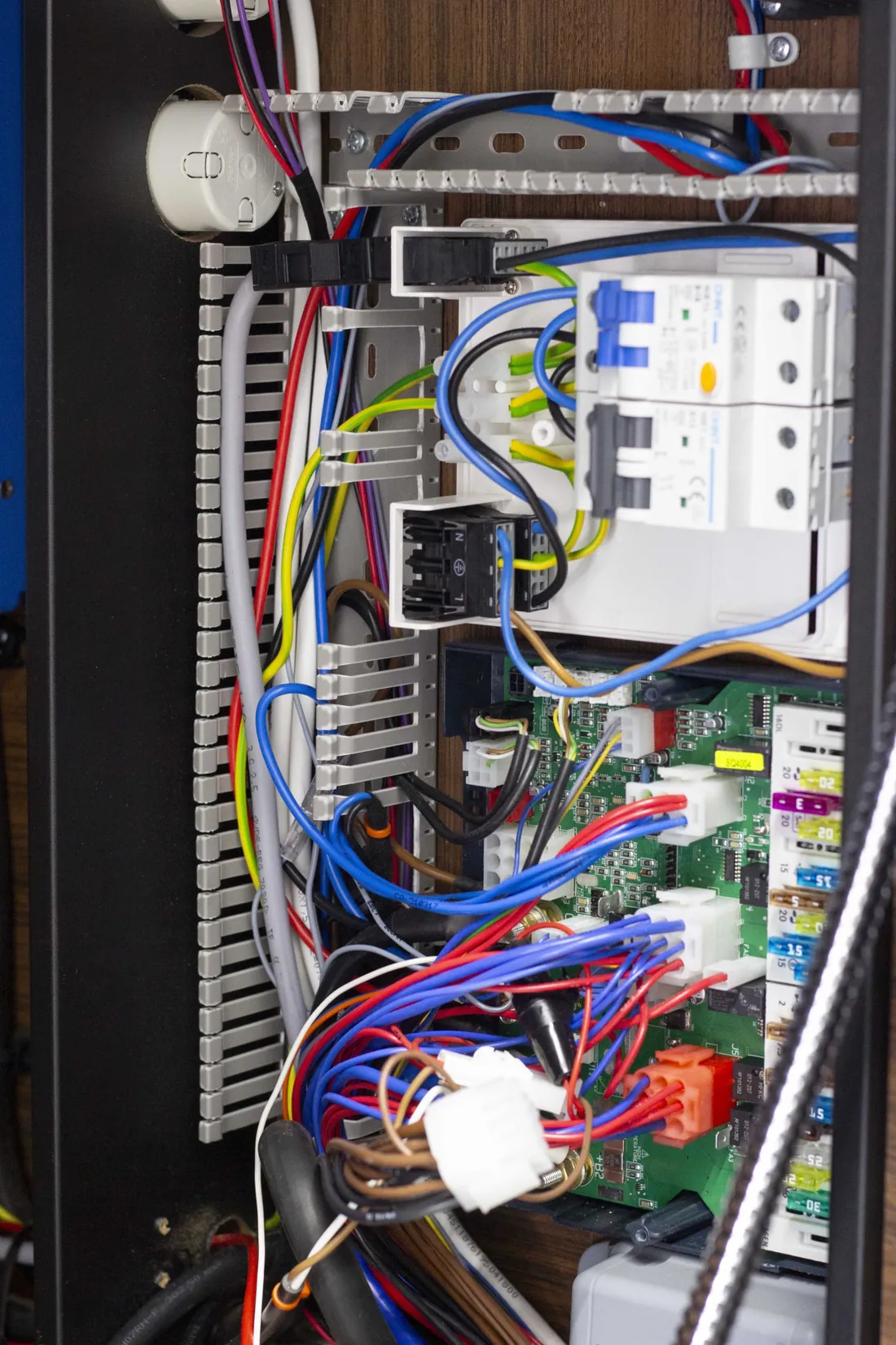 Blick in den Elektrikbereich eines Reisemobils mit Sicherungen, Verteiler und gebündelten Kabeln