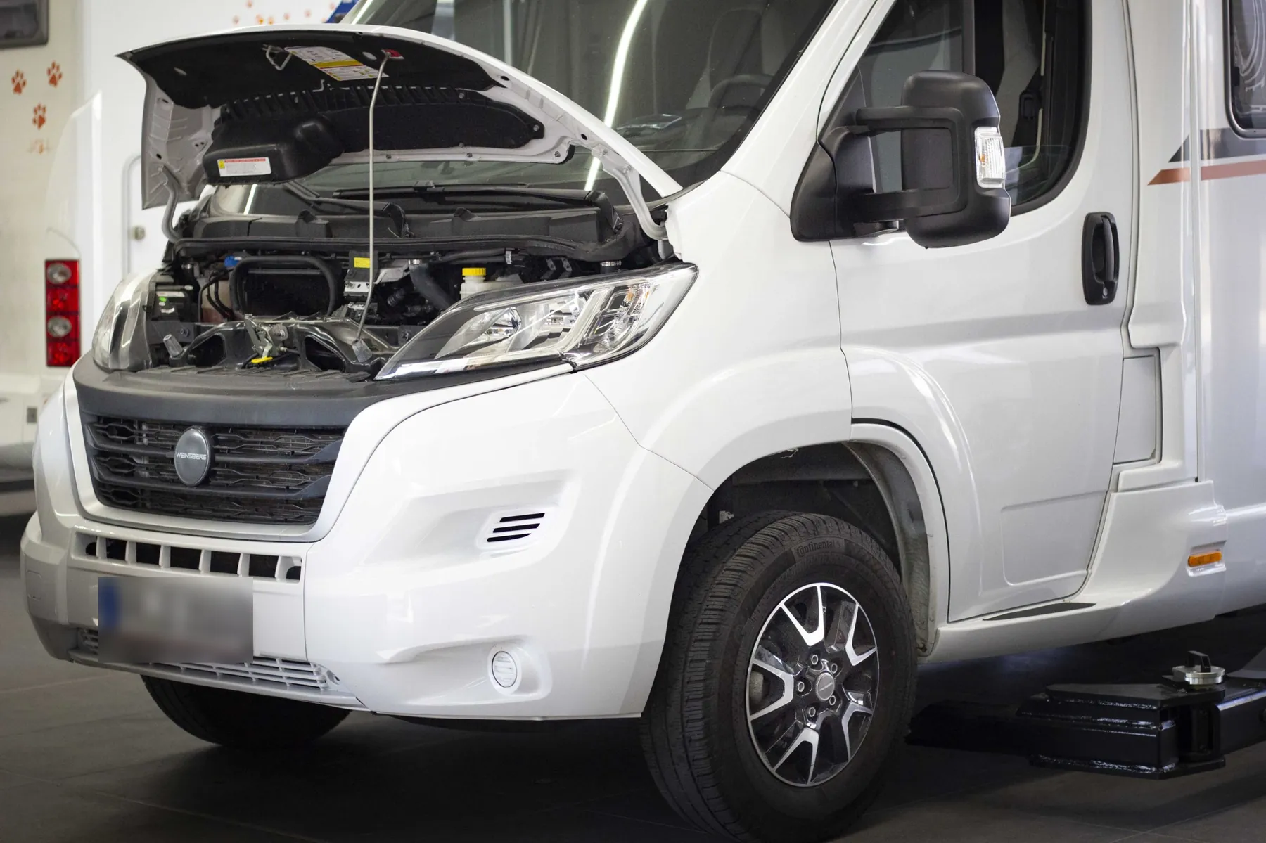 Weißes Reisemobil mit geöffneter Motorhaube in der Werkstatt